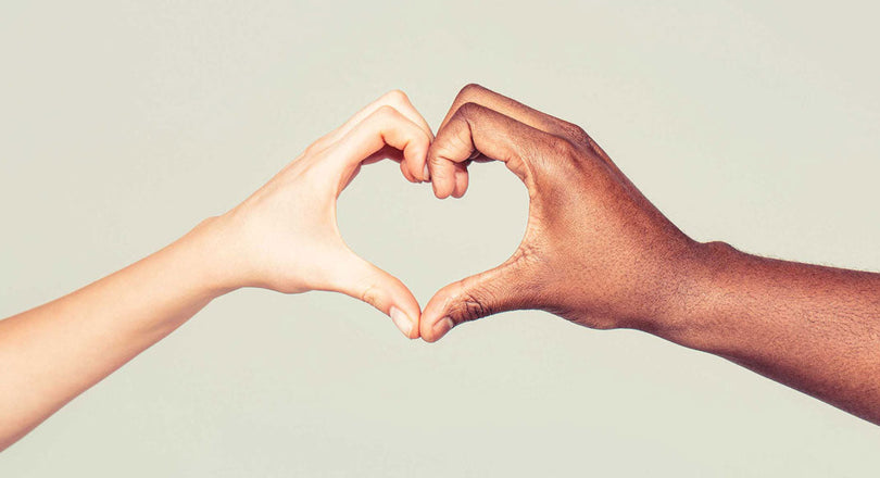 Zwei Hände unterschiedlicher Hautfarbe formen gemeinsam ein Herz