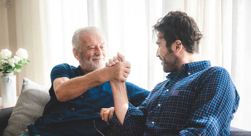 Zwei Männer sitzen nebeneinander und schlagen mit ihren Händen ein