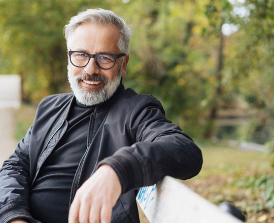 Mann sitzt auf einer Parkbank und lächelt in die Kamera