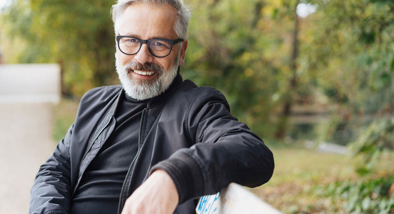 Mann sitzt auf einer Parkbank und lächelt in die Kamera