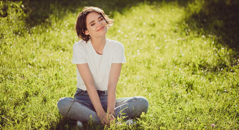 Frau sitzt im Gras und lächelt