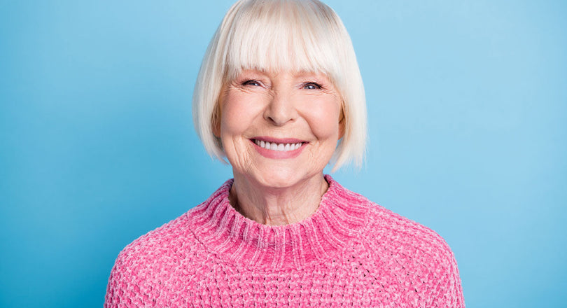 Frau mit pinkem Pullover lacht in die Kamera