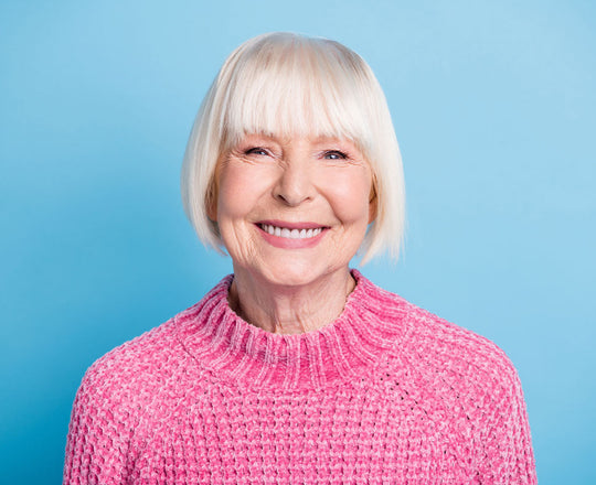 Frau mit pinkem Pullover lacht in die Kamera