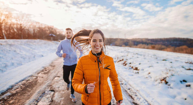 Frau und Mann laufen gemeinsam in einer Winterlandschaft