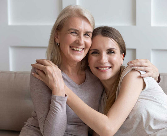 Zwei Frauen sitzen nebeneinander und umarmen sich
