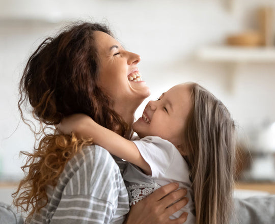 Ein Mädchen umarmt ihre Mama, beide lachen
