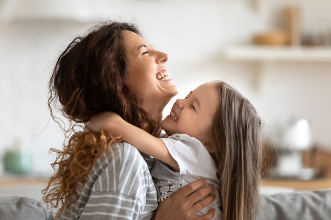 Ein Mädchen umarmt ihre Mama, beide lachen