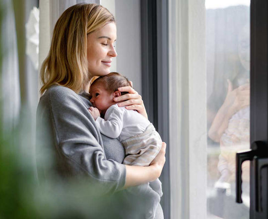 Fürsorgliche Mama hält ihr Baby auf dem Arm