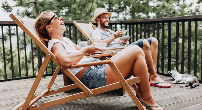 Eine Frau und ein Mann sitzen nebeneinander in Liegestühlen und lachen
