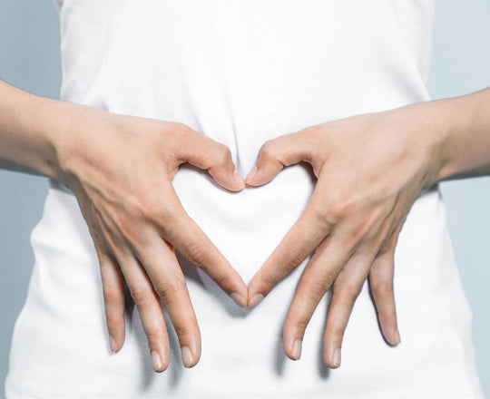 Frau formt mit ihren Händen ein Herz vor ihrem Bauch