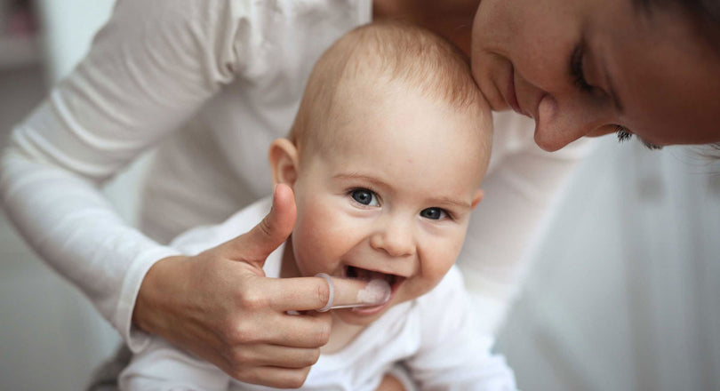 Eine Mutter putzt ihrem Baby vorsichtig die ersten Zähnchen