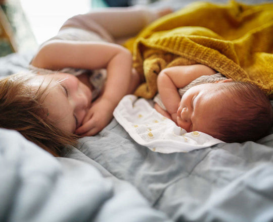 Baby und Kleinkind liegen schlafend zusammen in einem Bett