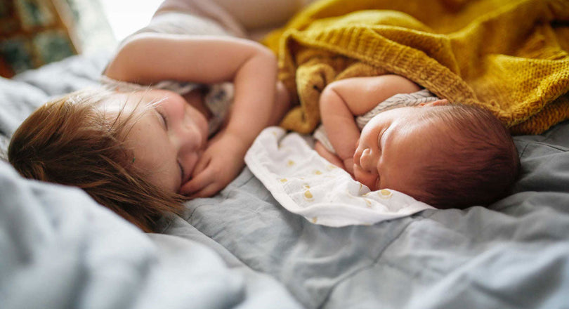 Baby und Kleinkind liegen schlafend zusammen in einem Bett