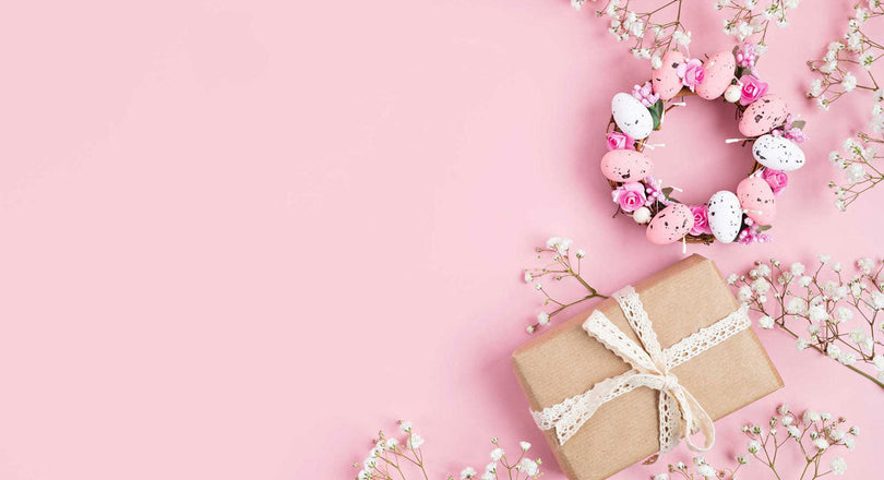 Geschenke, Blumen und Ostereier auf einem rosa Untergrund