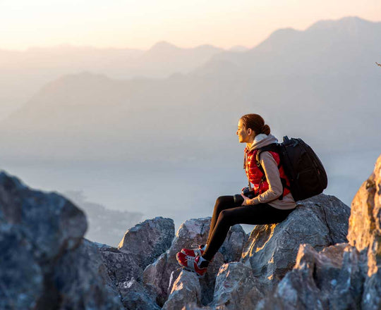 Frau sitzt im Herbst auf einem Felsen in den Bergen