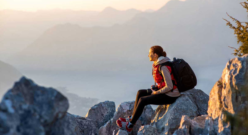Frau sitzt im Herbst auf einem Felsen in den Bergen