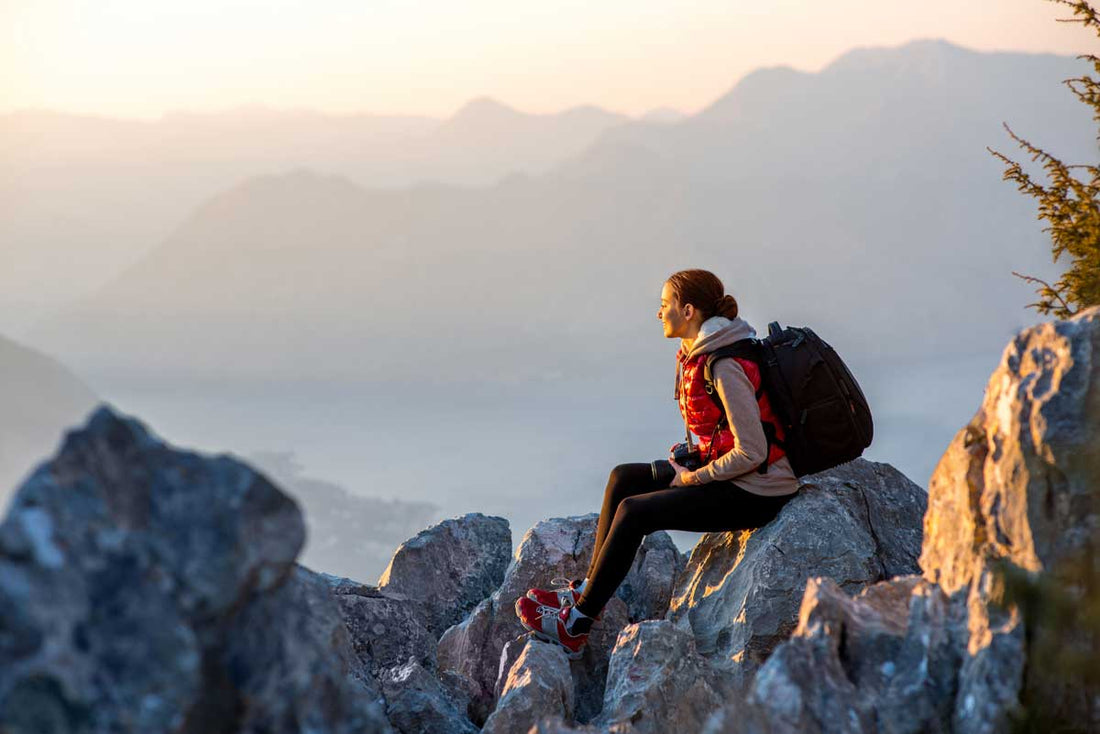 Frau sitzt im Herbst auf einem Felsen in den Bergen
