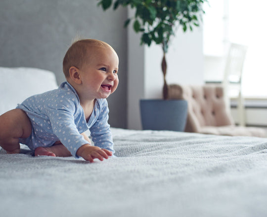 Krabbelndes und lächelndes Baby auf einem Bett