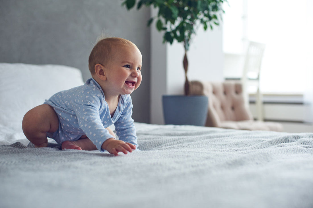 Krabbelndes und lächelndes Baby auf einem Bett