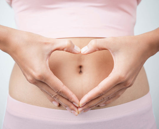 Frau formt mit ihren Händen ein Herz vor ihrem Bauch