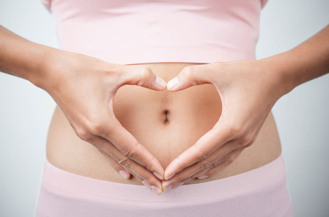 Frau formt mit ihren Händen ein Herz vor ihrem Bauch