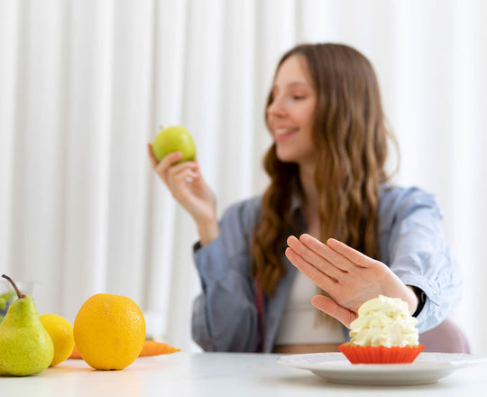 Frau schiebt einen Muffin zur Seite und hält einen Apfel in der Hand